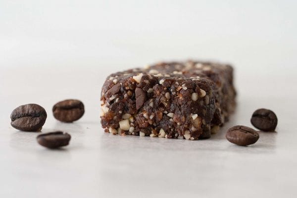 Plate of dark brown vegan Mocha Chip Bars, some shaped into balls and others as squares, with visible chocolate chips, ready to be enjoyed.