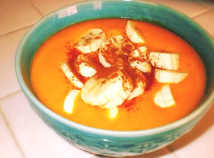 A vibrant orange Mango Butternut Squash Soup, garnished with fresh mango cubes and a sprinkle of cinnamon, served in a white bowl.