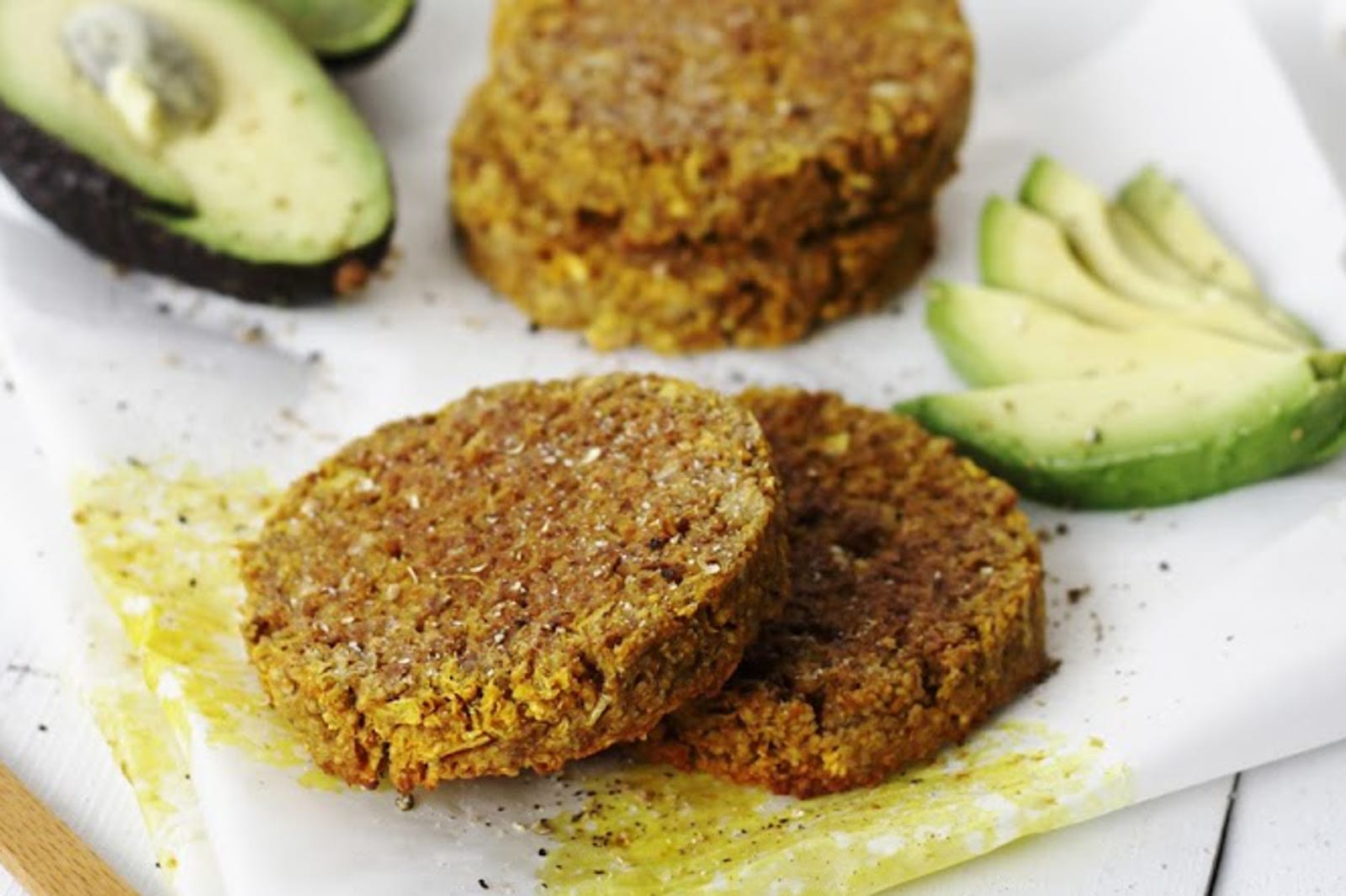 A stack of Jicama Burgers, seasoned with cumin and dill, served on a plate with fresh herbs, avocado slices, and crisp greens.