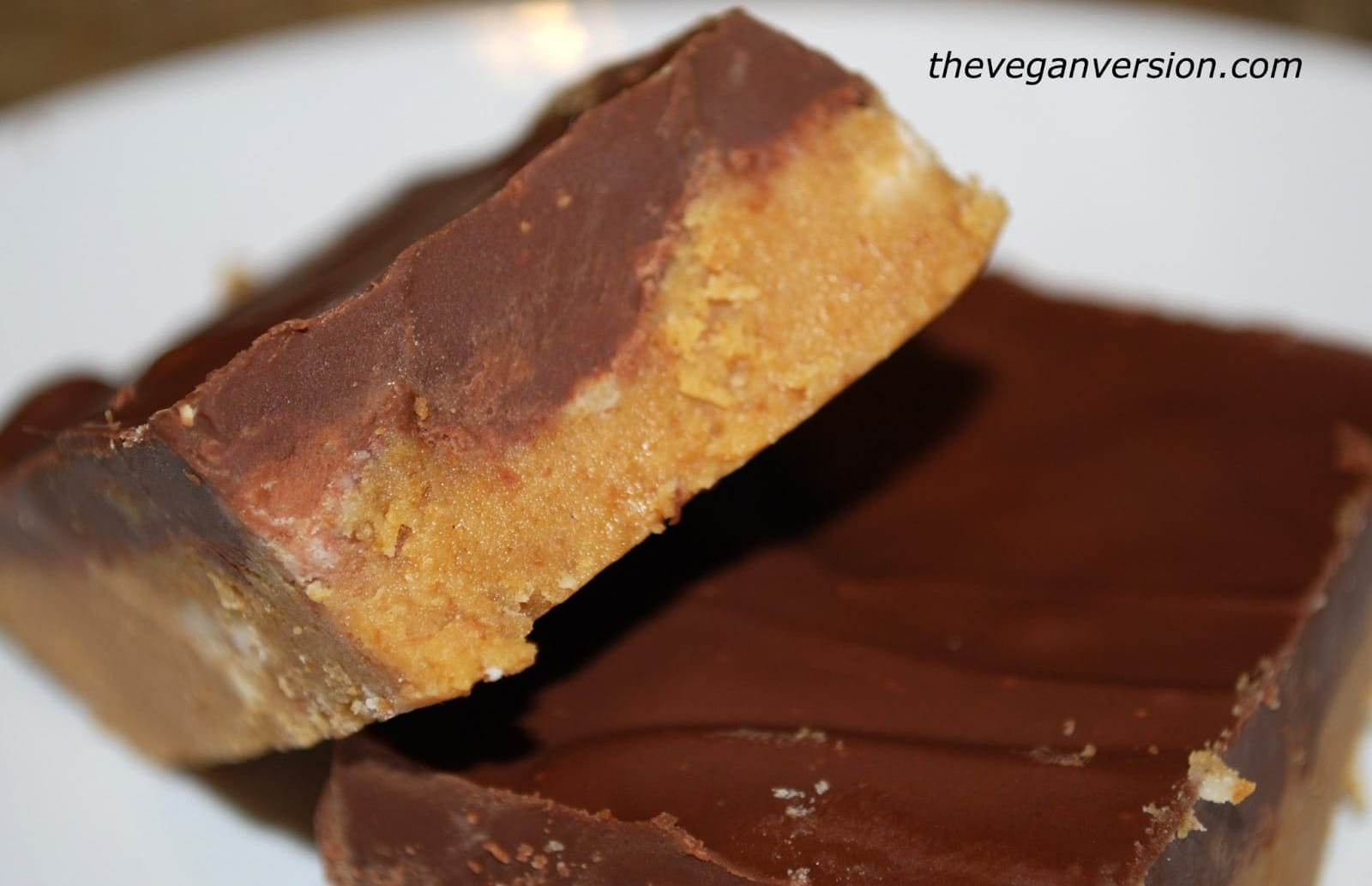 Close-up of a stack of three square vegan Peanut Butter Bars, showing the distinct graham cracker base and smooth chocolate-peanut butter topping, ready to serve.