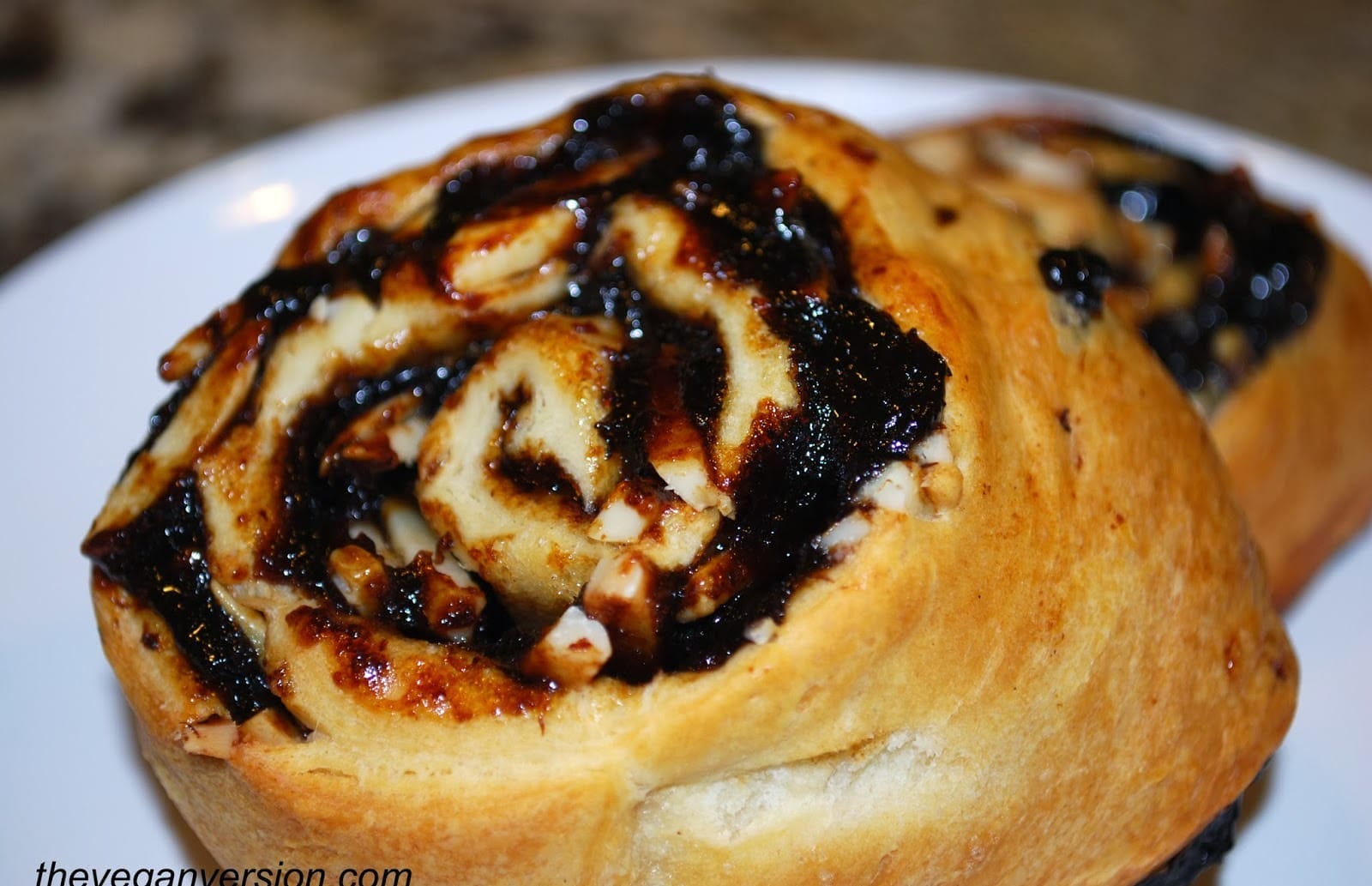 Six golden-brown vegan Almond Prune Danishes, topped with toasted slivered almonds, arranged on a lightly greased cookie sheet.
