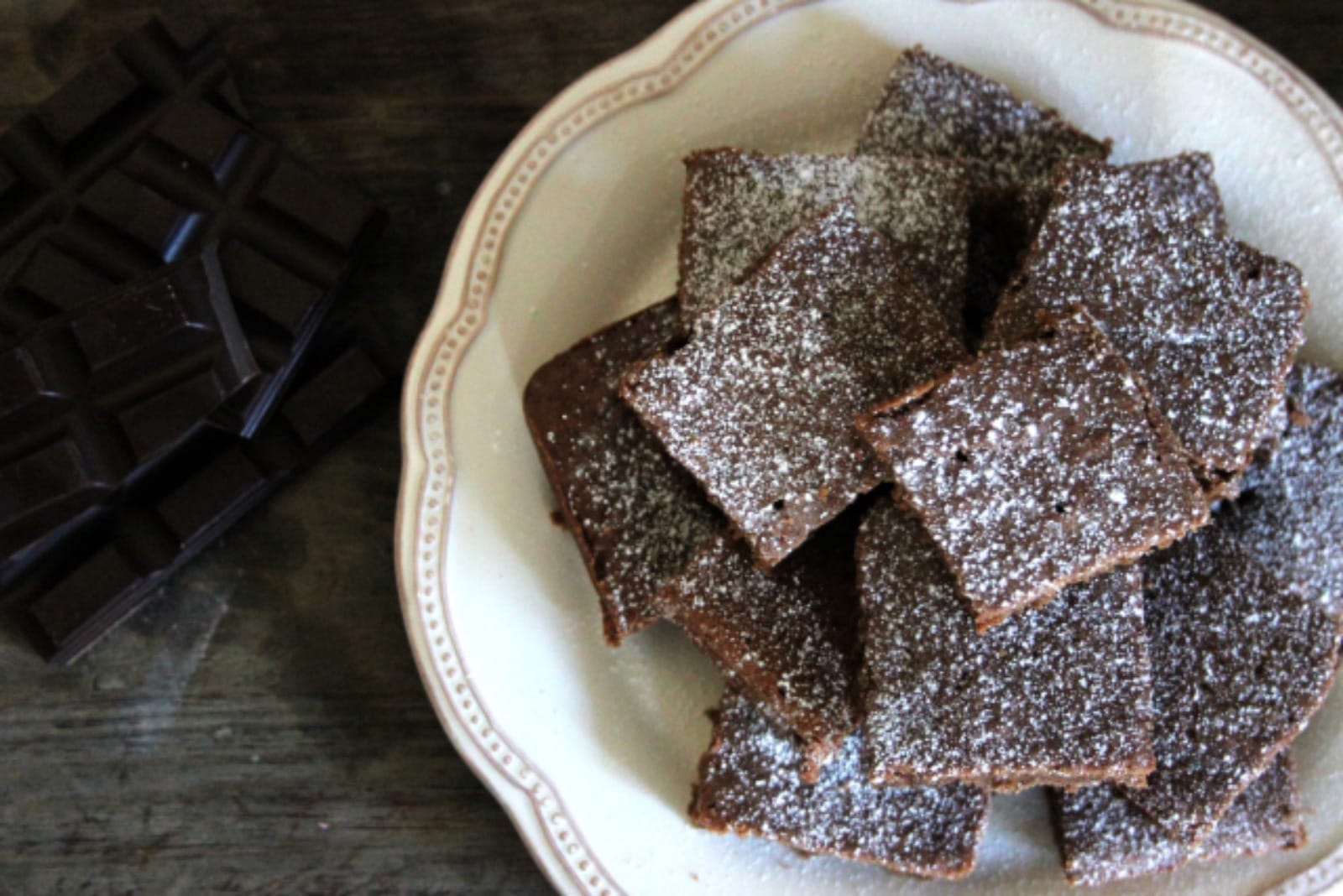 A generous slice of rich, dark vegan chocolate spice cake, visibly moist with warm spices, served on a white plate, ready to enjoy.