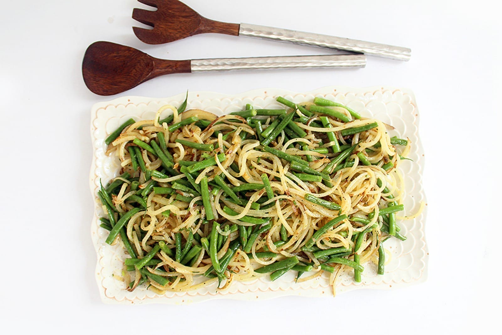 A vibrant vegan Potato Noodle and Green Bean Salad, tossed with a zesty vinaigrette and garnished with fresh chives, served in a white bowl.