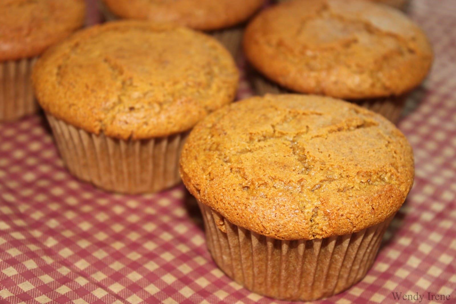 Close-up of freshly baked vegan gluten-free pumpkin muffins, golden brown with a hint of spice, arranged on a cooling rack.