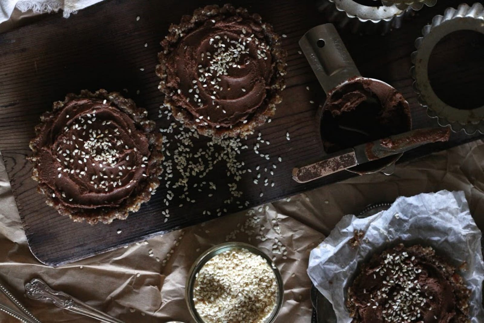 Close-up of a single Salted Caramel and Sesame Chocolate Cream Tart, topped with sesame seeds, on a white plate.