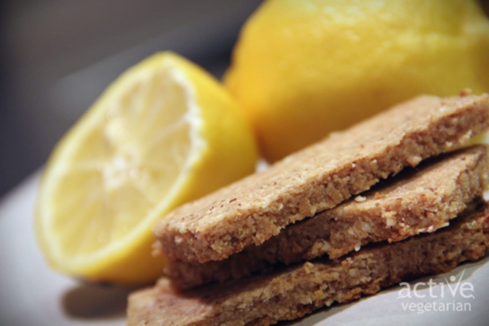 A close-up of several golden-brown Toasted Coconut Cream Bars, sliced into squares, with visible toasted coconut flakes and a hint of lemon zest, arranged on a rustic serving board.