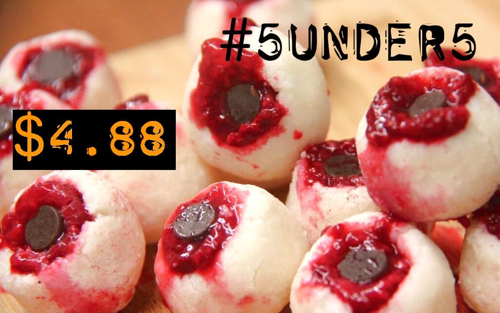 A plate of spooky vegan Bloody Coconut Raspberry Monster Eyeballs, each with a raspberry "iris" and chocolate chip "pupil," splattered with red raspberry juice for a gruesome effect.
